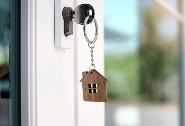A key in the lock of a door with a key ring of a house showing that it is secure. 