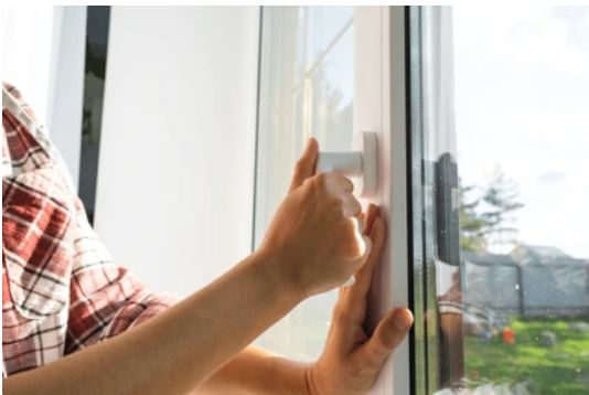 Person adjusting a window handle, addressing common window problems with old uPVC windows. 